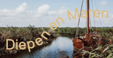 Een riviertje door een groen landschap met een houten zeilbootje.