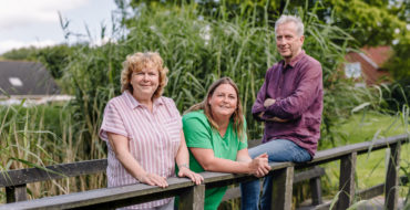 Twee vrouwen en een man op een brug, poserend voor de camera.