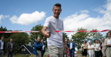 Man in wit t-shit knip lint door.