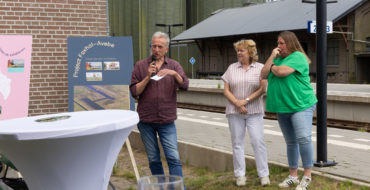 Drie mensen naast twee presentatieborden. Op de achtergrond is het treinstation van Zuidbroek te zien.