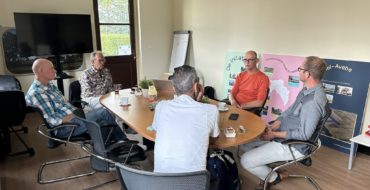 Vijf mensen rond een tafel. Ze zijn met elkaar in gesprek.