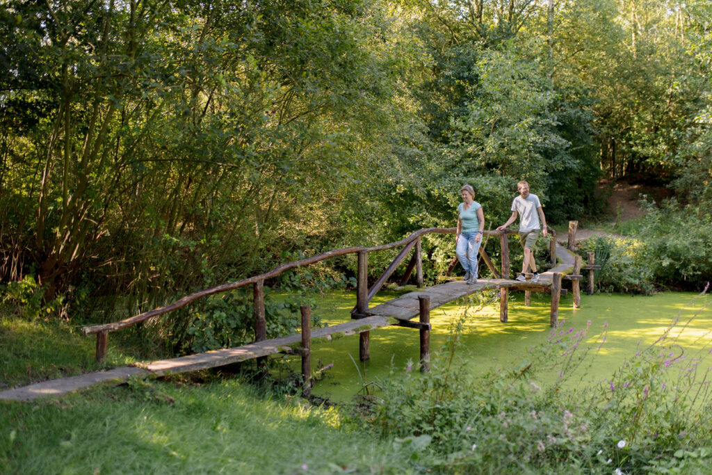 Een man en een vrouw lopen over een brug van hout,