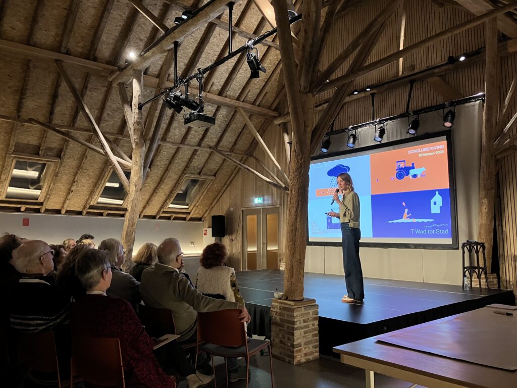 Vrouw staat op een podium voor publiek.