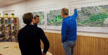 3 mannen kijken naar grafisch weergegeven posters op de muur.